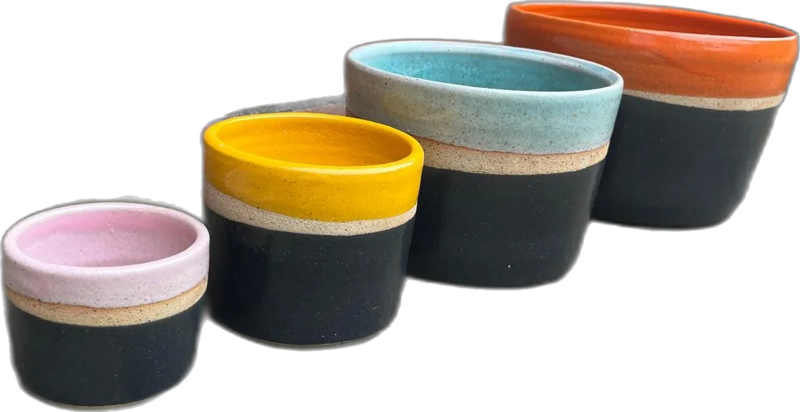 Four hand thrown pots in pink, yellow, blue and orange glaze, arranged by size